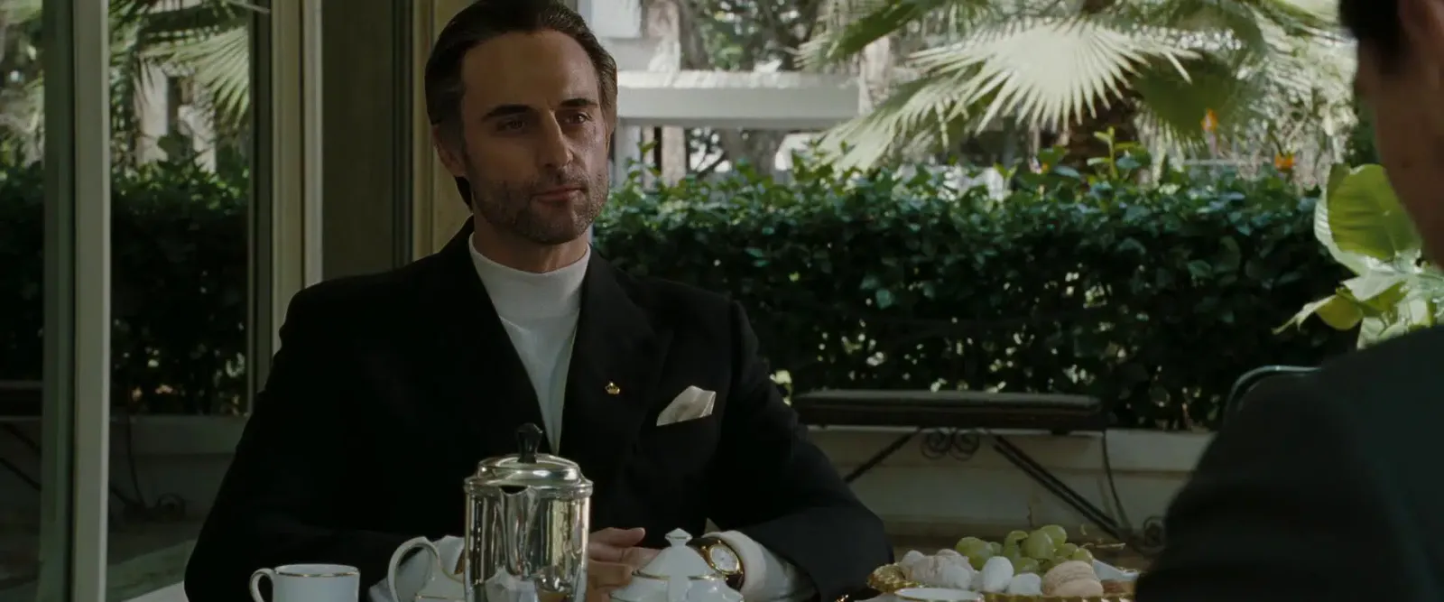 A man in brown face sits at a cafe table