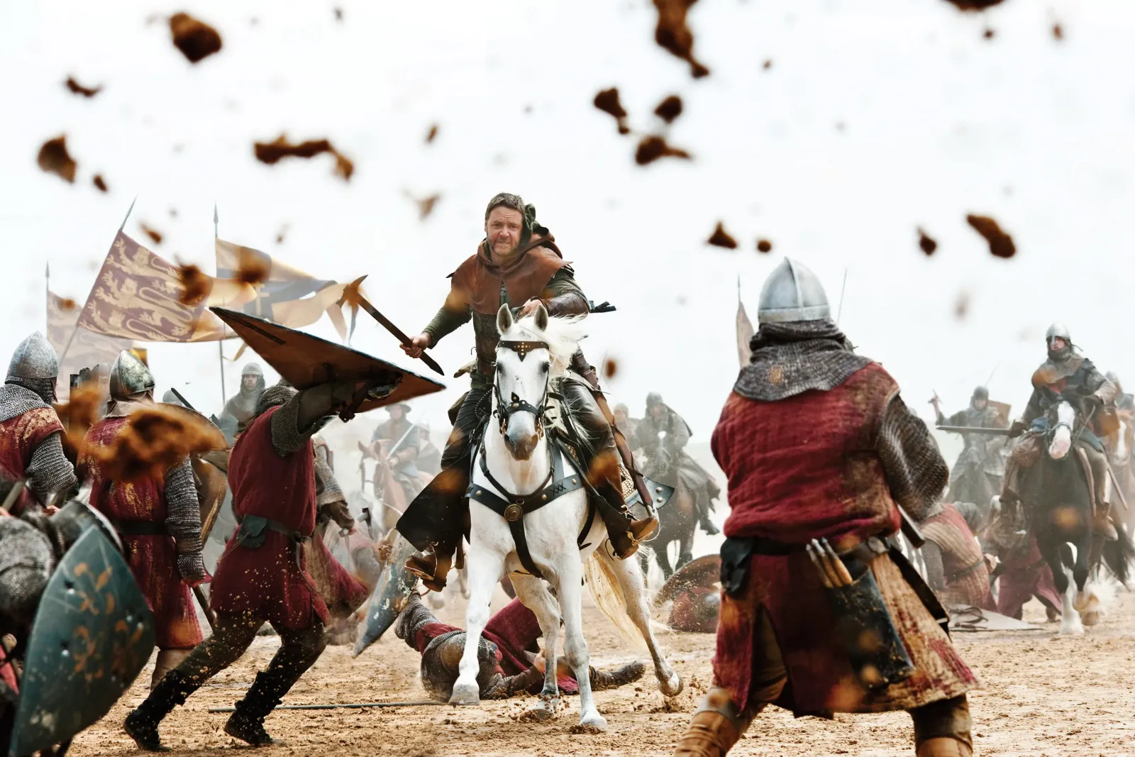 A warrior on horseback charges across a beach toward armoured soldiers