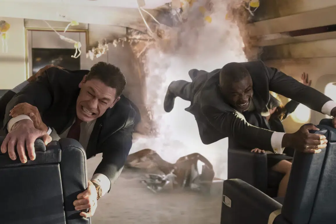 two men holding onto the seats, about to be sucked out of a hole in the side of a plane